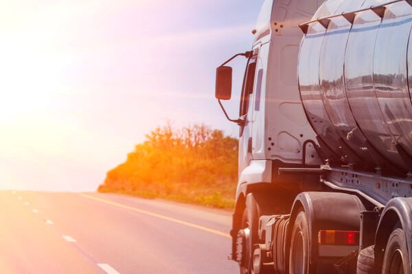 Imagen de un camión de transporte de mercancías circulando por una carretera principal, reflejando la importancia del transporte por carretera en la cadena de suministro internacional